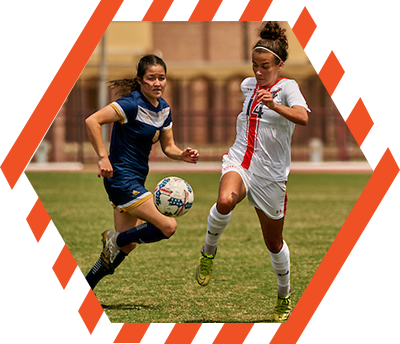 two female soccer players competing for the ball