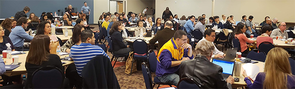 recent grant writing workshop participants sitting at round tables. 