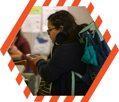 student carrying a back-pack and searching her cell phone