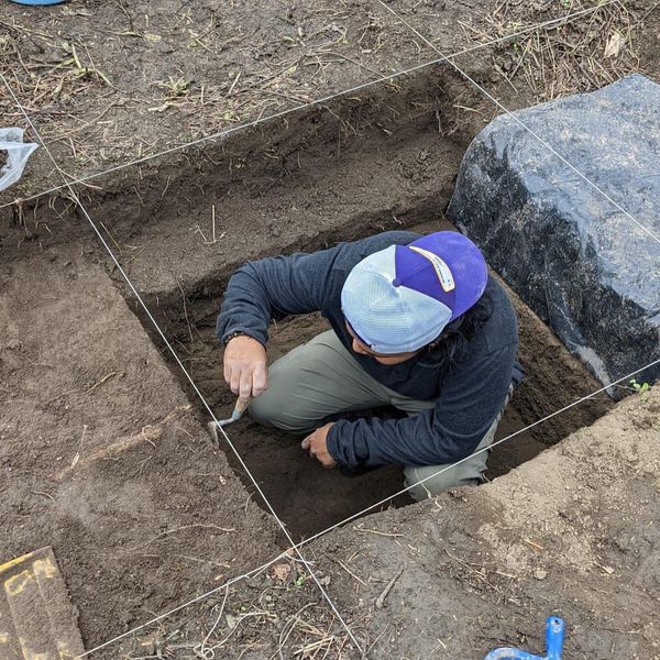 student excavating wearing baseball cap