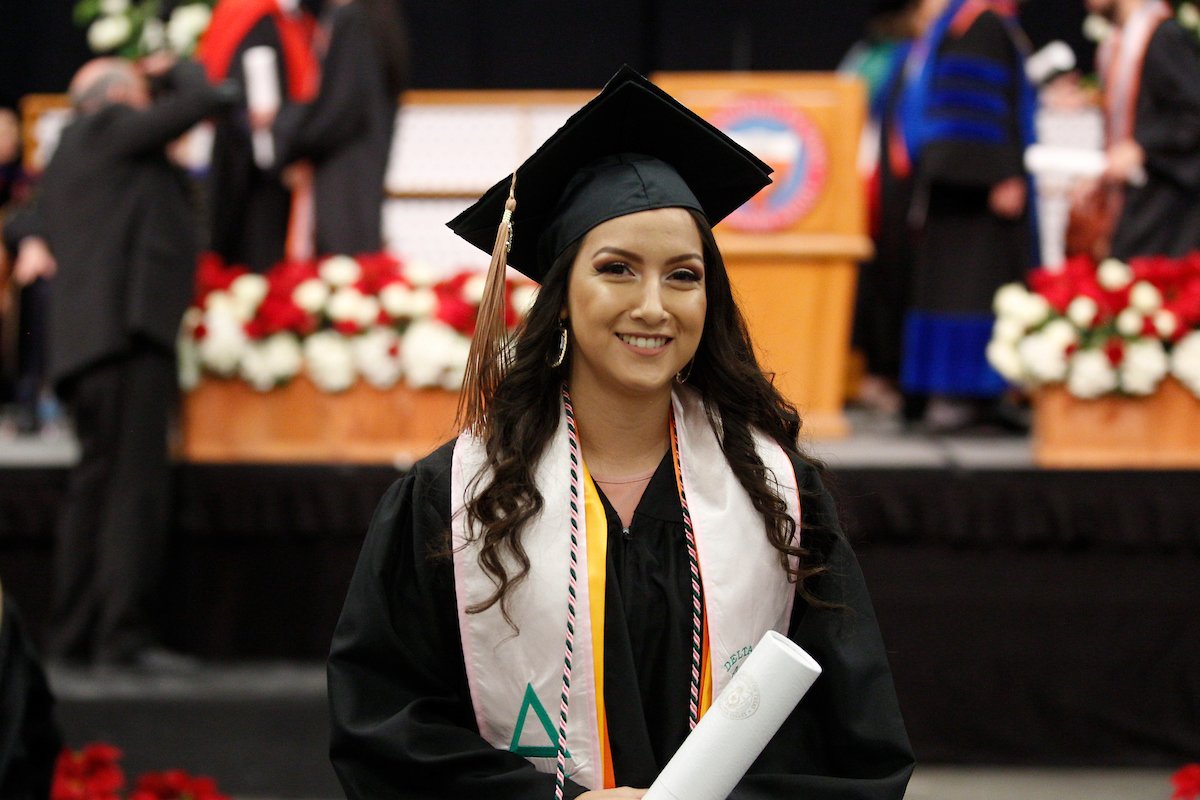 Student in cap and gown smiling to camera. Student in cap and gown smiling to camera.