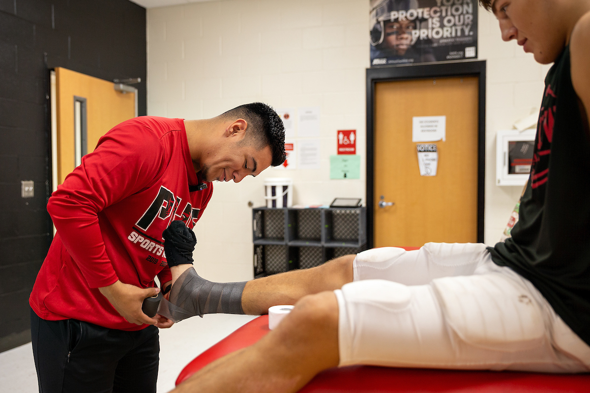 Professional works as an athletic's trainer helping students foot issue Professional works as an athletic's trainer helping students foot issue