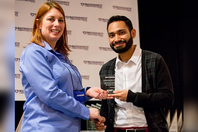 Milton Hernandez, program coordinator in the UTRGV Office of Community Relations, here is seen accepting the Texas MATHCOUNTS Coordinator of the Year Award for 2017-2018, from Maryella Begley, P.E.(DOW) and state MATHCOUNTS committee chair.