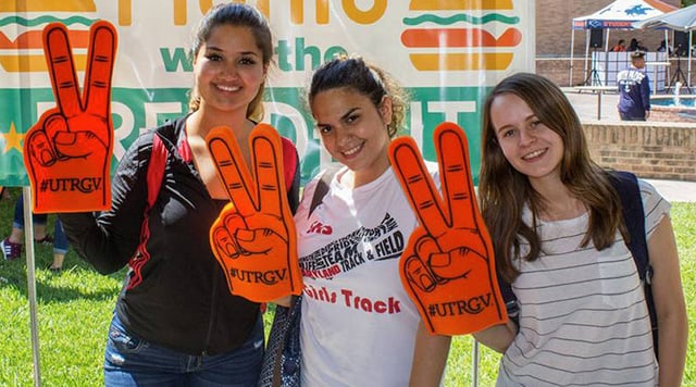 UTRGV students holding V's up foam hands.