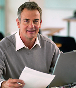 Educational Leadership instructor smiling while holding paper and a pen