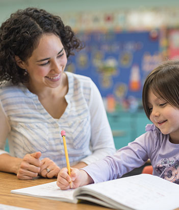 Special Education instructor smiling while assisting a student