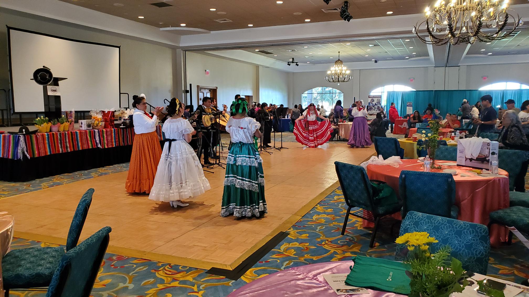 In a conference room, there are several female dancers with the folklore Mexican wardrobe.