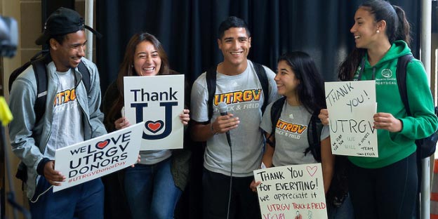 5 happy students holding thank you signs