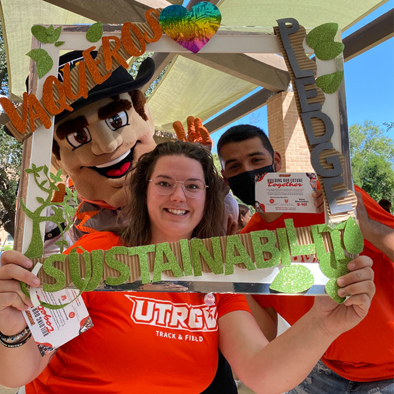 UTRGV Vaquero and two other students taking a photo with the Sustainability Pledge selfie frame during Campus Sustainability Day hosted by the Office for Sustainability 