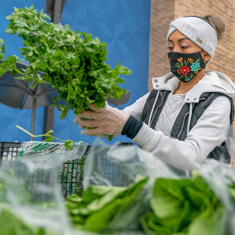 picture of a woman with a face mask holding produce
