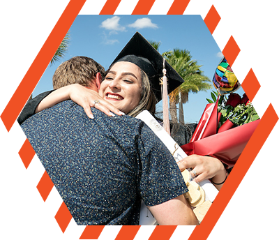 graduate holding balloons and flowers hugs her acquaintance