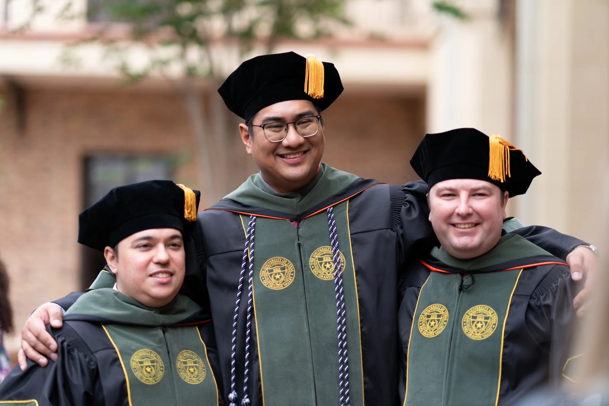 Three UTRGV School of Podiatric Medicine faculty members in academic regalia at commencement.