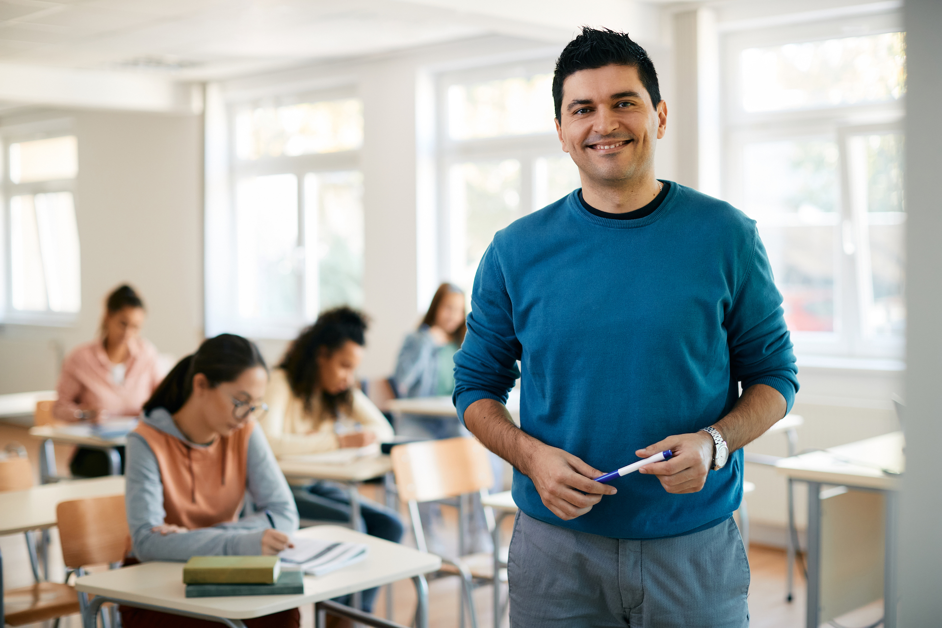 teacher smiling at camera in classroom with students