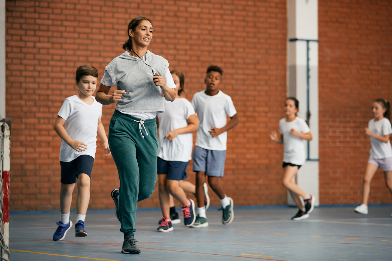 teacher running in gym with students
