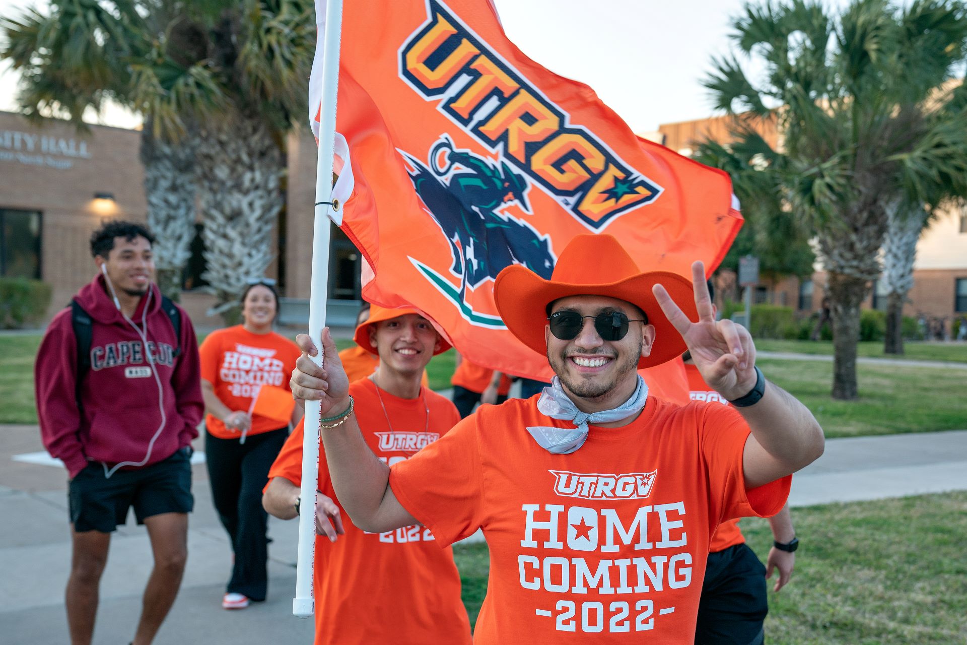 Male student representing UTRGV and holding school flag
