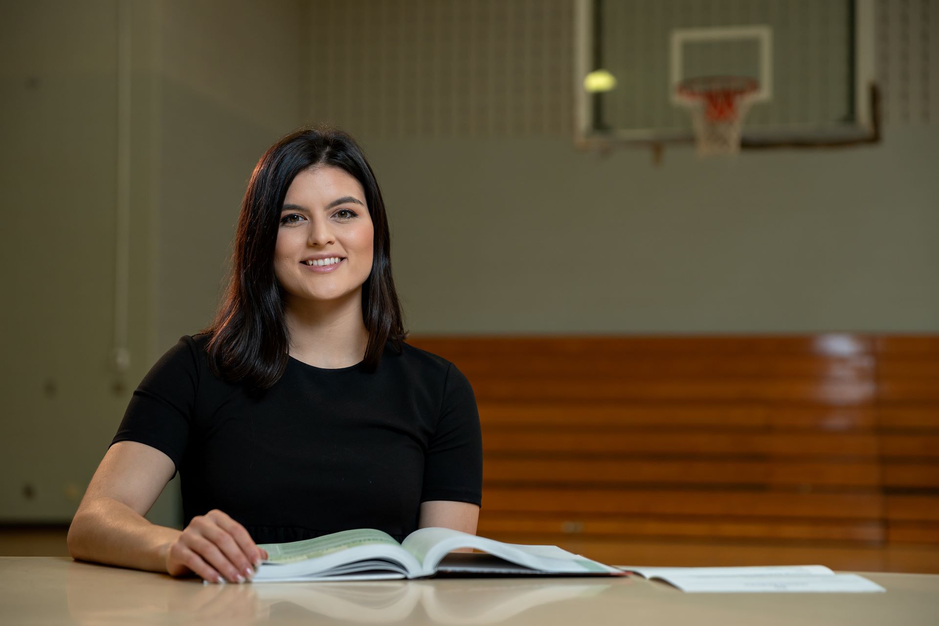 Female student smiling in front of basketball court
