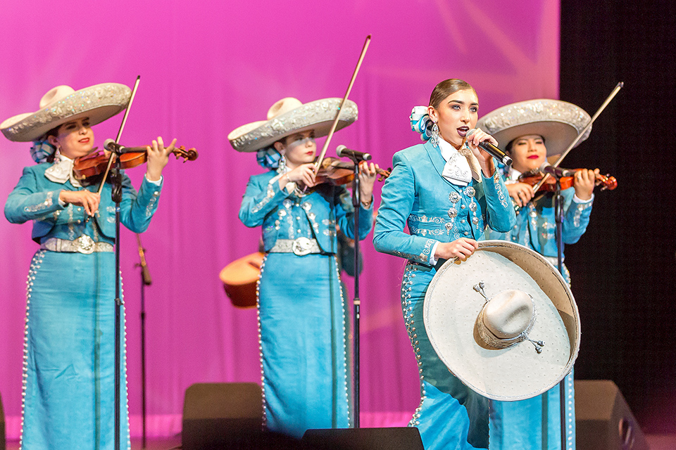 mariachi singing and playing instruments on stage