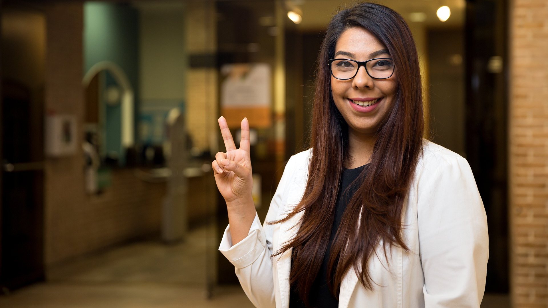 female nursing student smiling at camera with v's up
