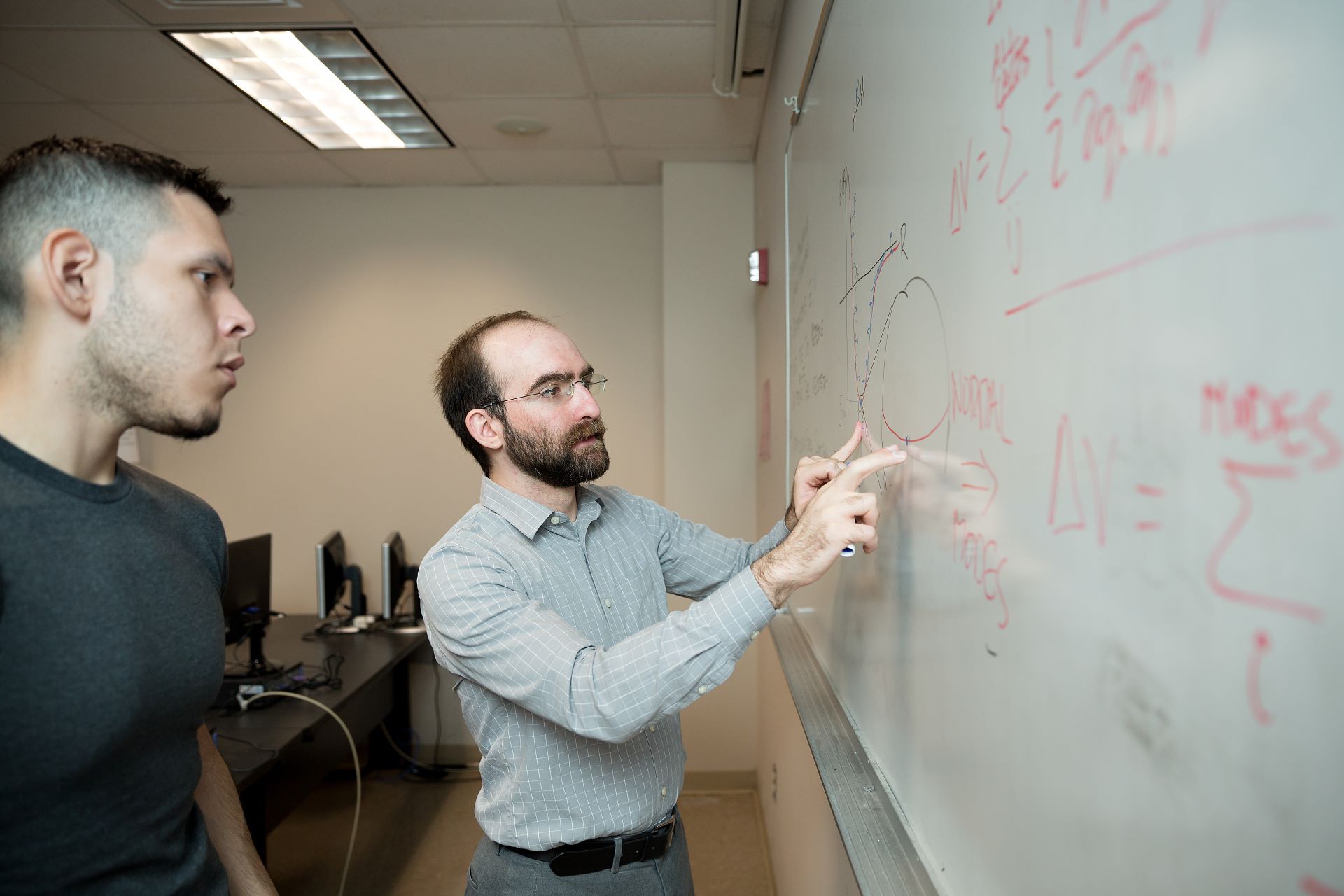 Professor showing student equations on white board