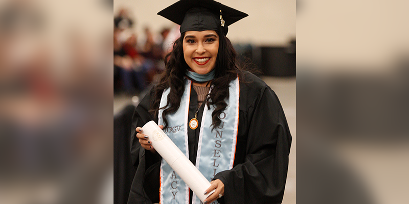 Female graduate student in regalia holding her degree