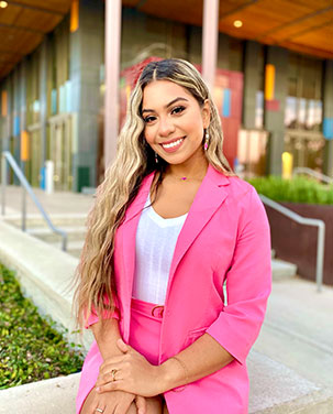 Priscilla Espinoza sitting in front of UTRGV Performing arts building