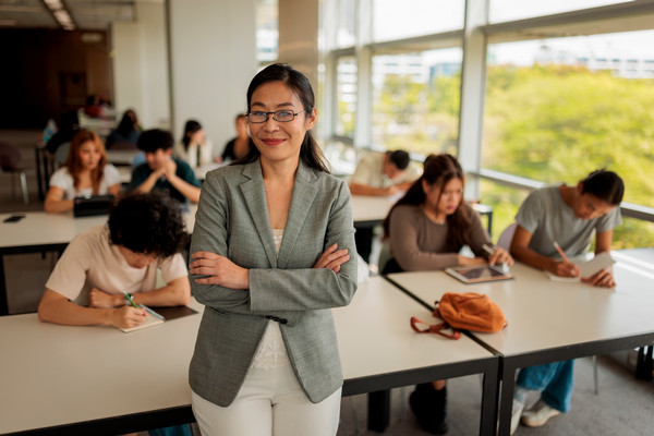 woman in a classroom with students reading behind her