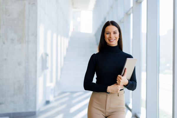 Young professional woman smiling at camera with a binder