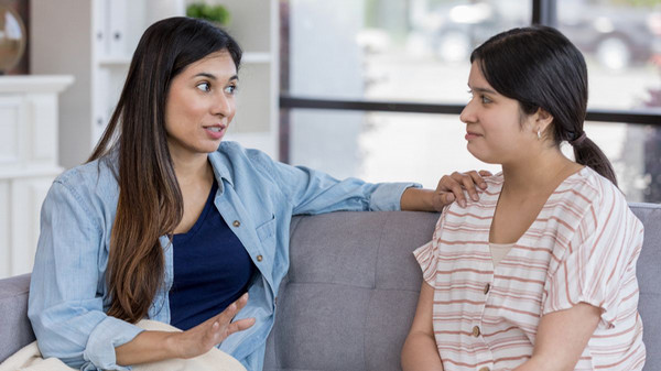 Two women having a conversation in their living room.