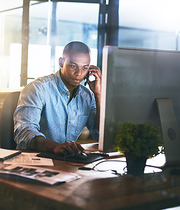 MBA student on the phone, sitting in front of a computer