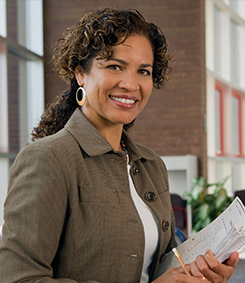 Special Education instructor smiling while holding a book and pencil