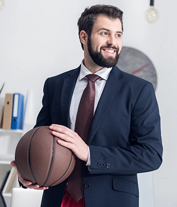Man in suit inside an office environment holding a basketball.