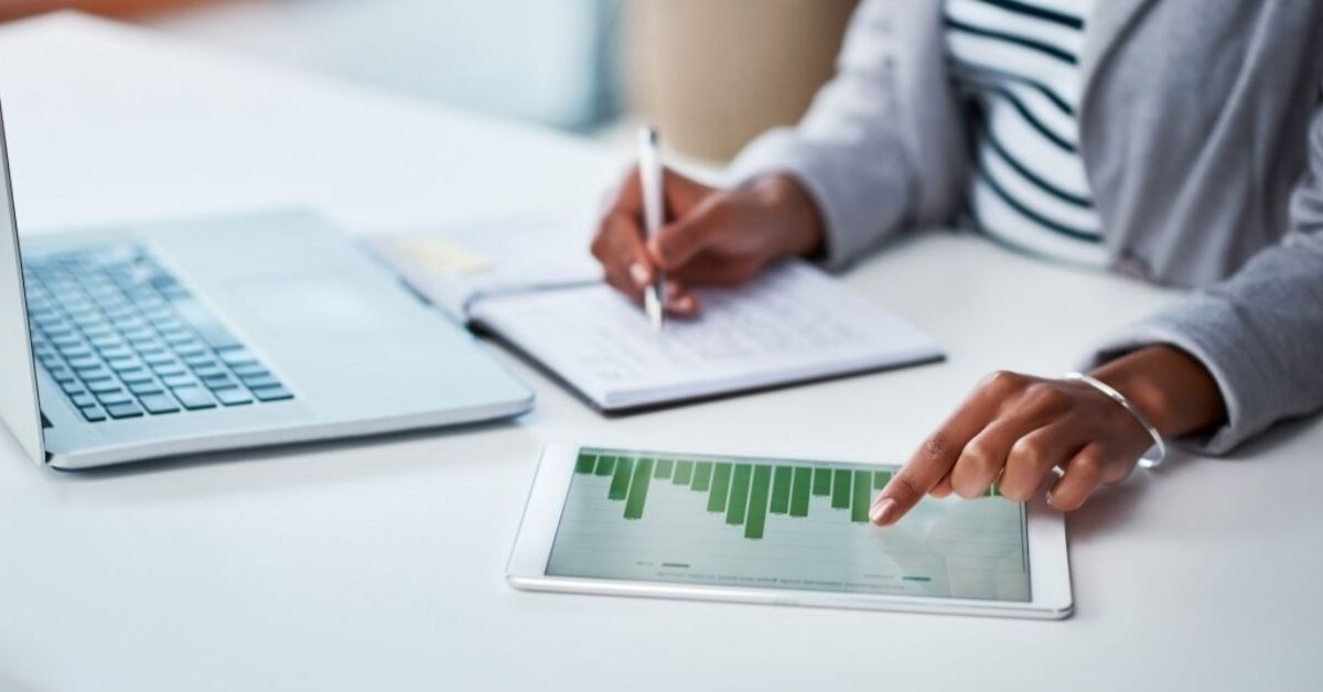 Business analytics expert looking at a iPad with chart data displaying on the screen.