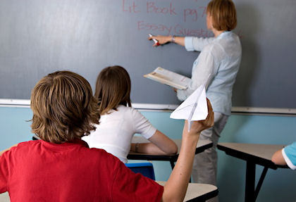 Student holding paper airplane during a lecture