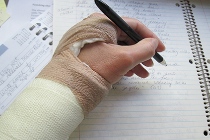 Hand in cast holding a pencil