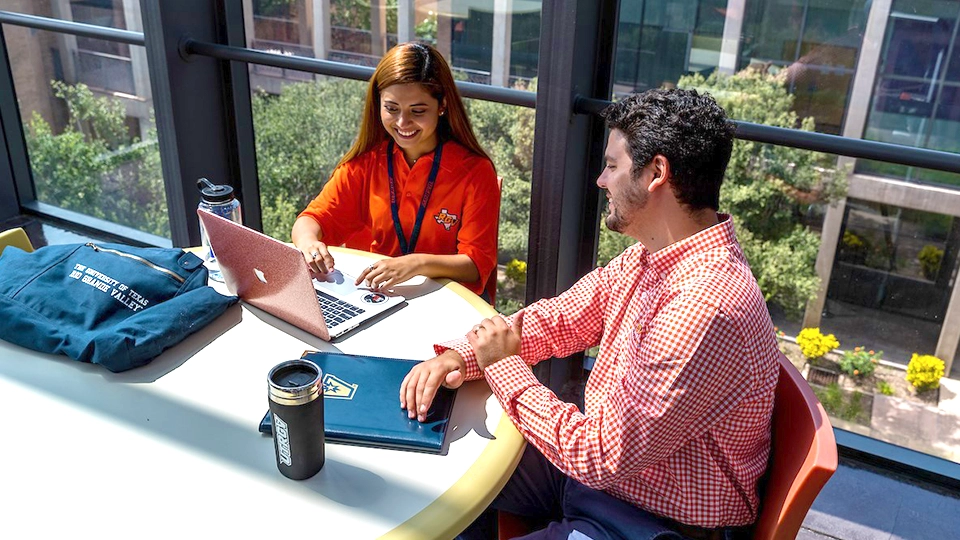 Two students sitting with a laptop.