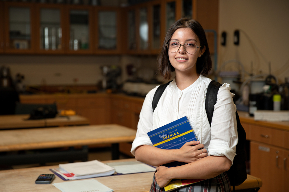 Student in lab hugging a book.