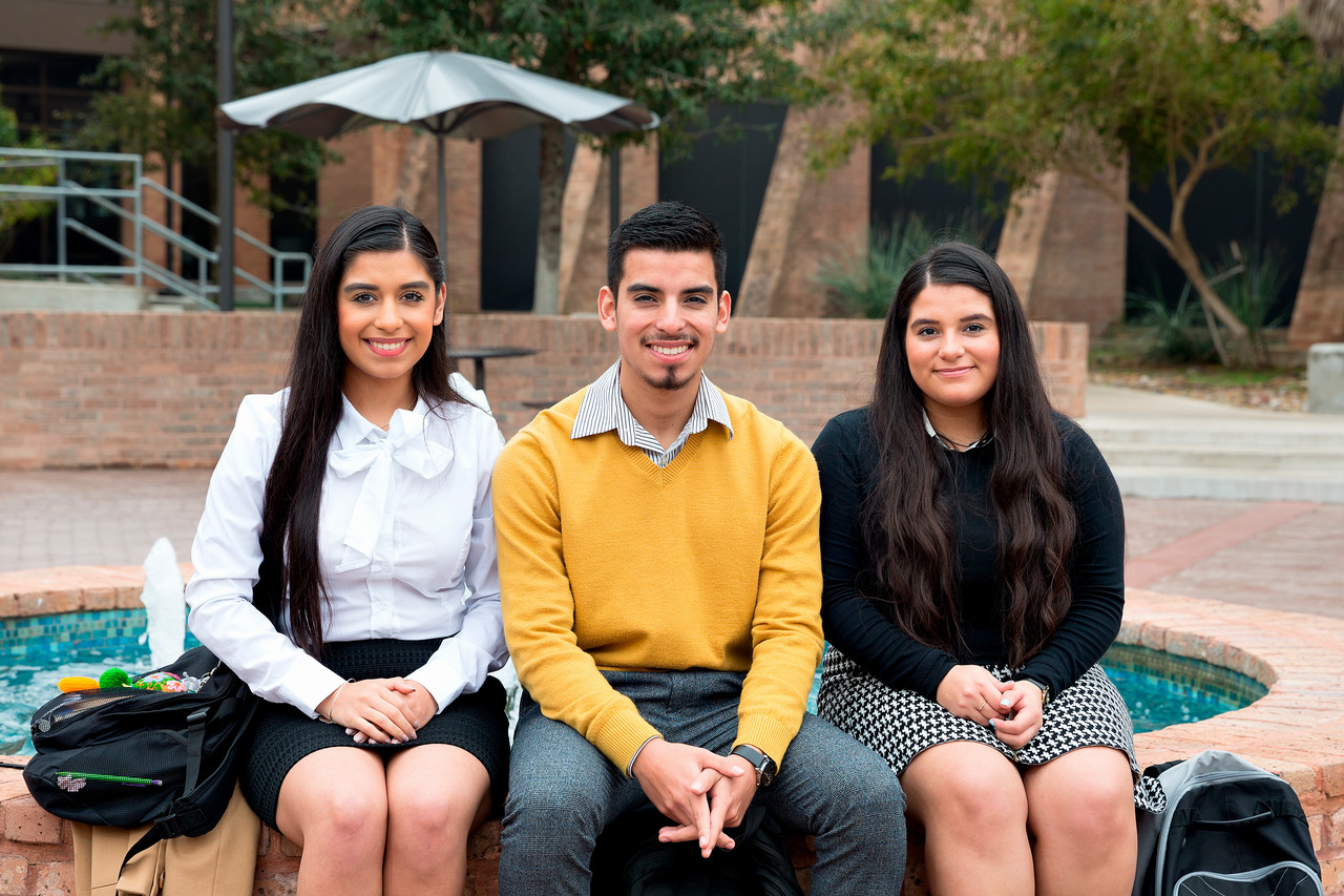 Three students sitting and smiling.