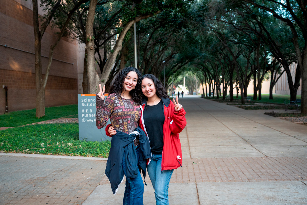 Two students smiling and holding V's Up!