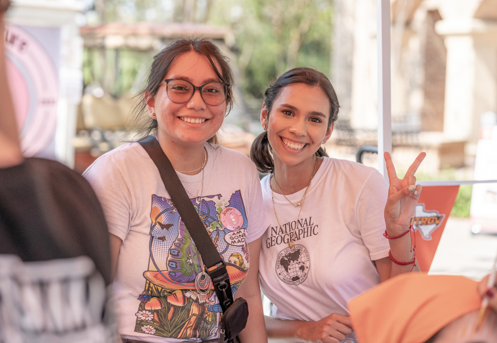 Two students smiling, one holding V's Up!