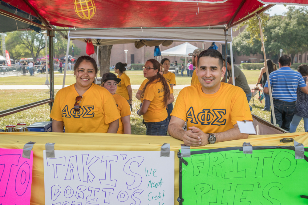 Two students sitting at an event booth on campus.
