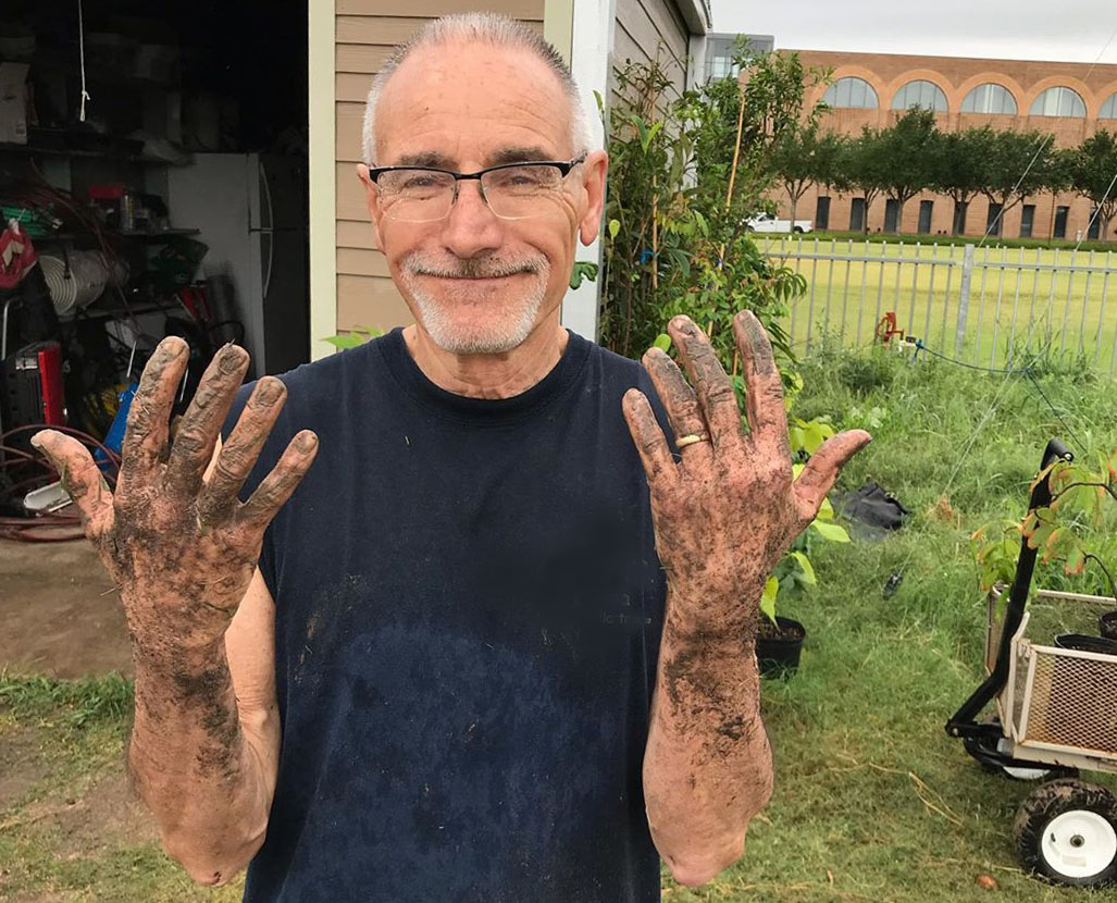 Volunteer shows off his muddy hands with a smile on his face.