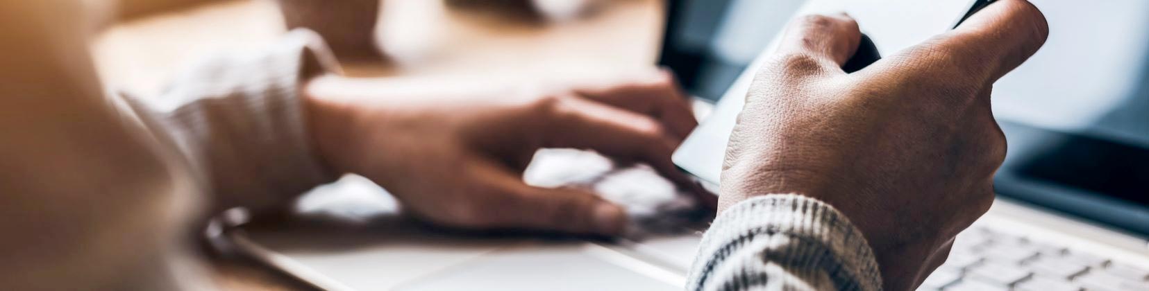 man checking phone and using laptop