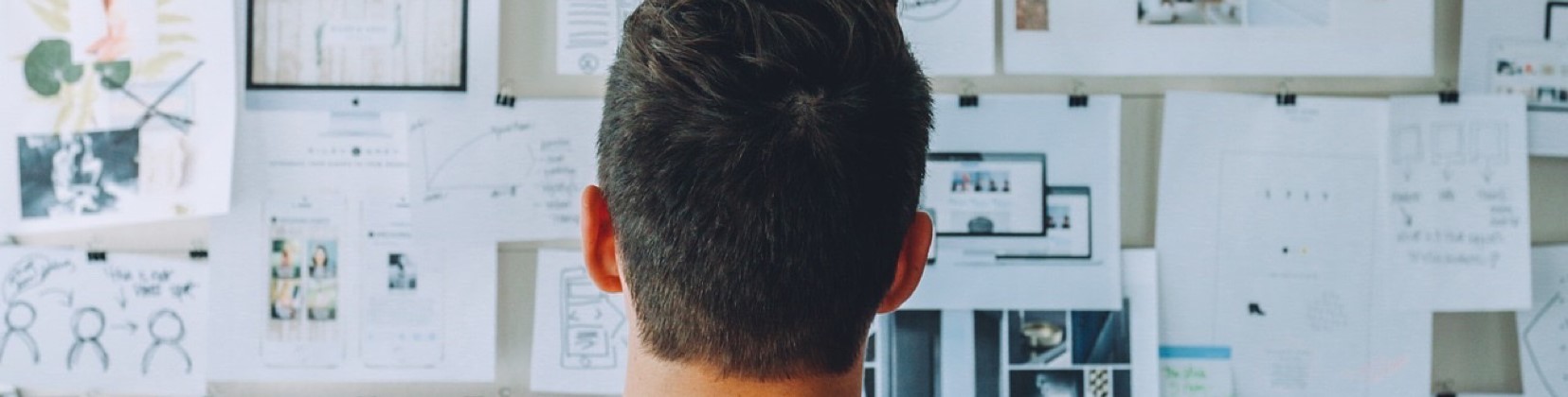 man standing in front board of board looking at research papers and projects