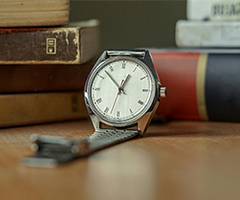 A watch leaning against a stack of books