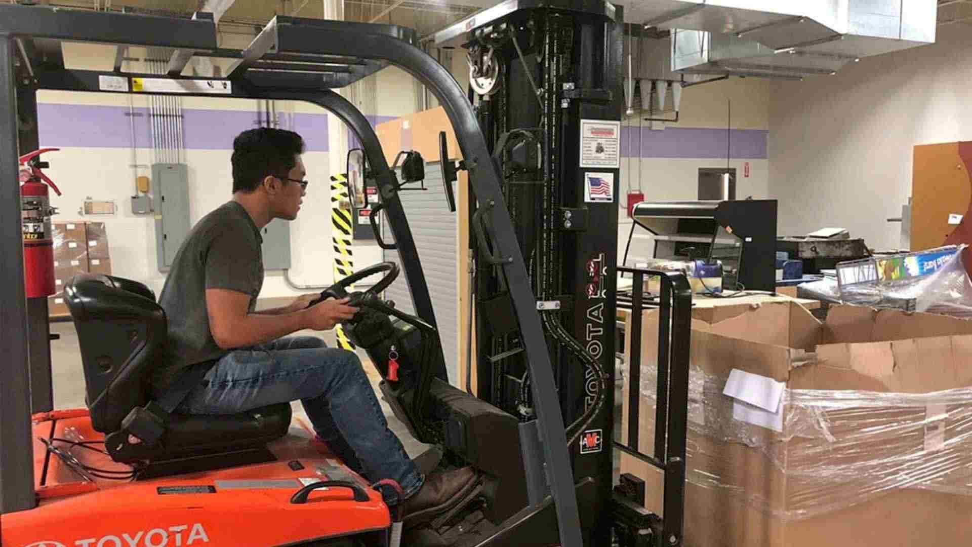 man in forklift lifting a box for forklift training