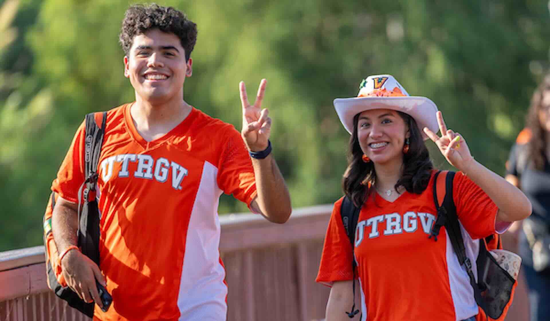 students wearing UTRGV shirts holding up peace signs