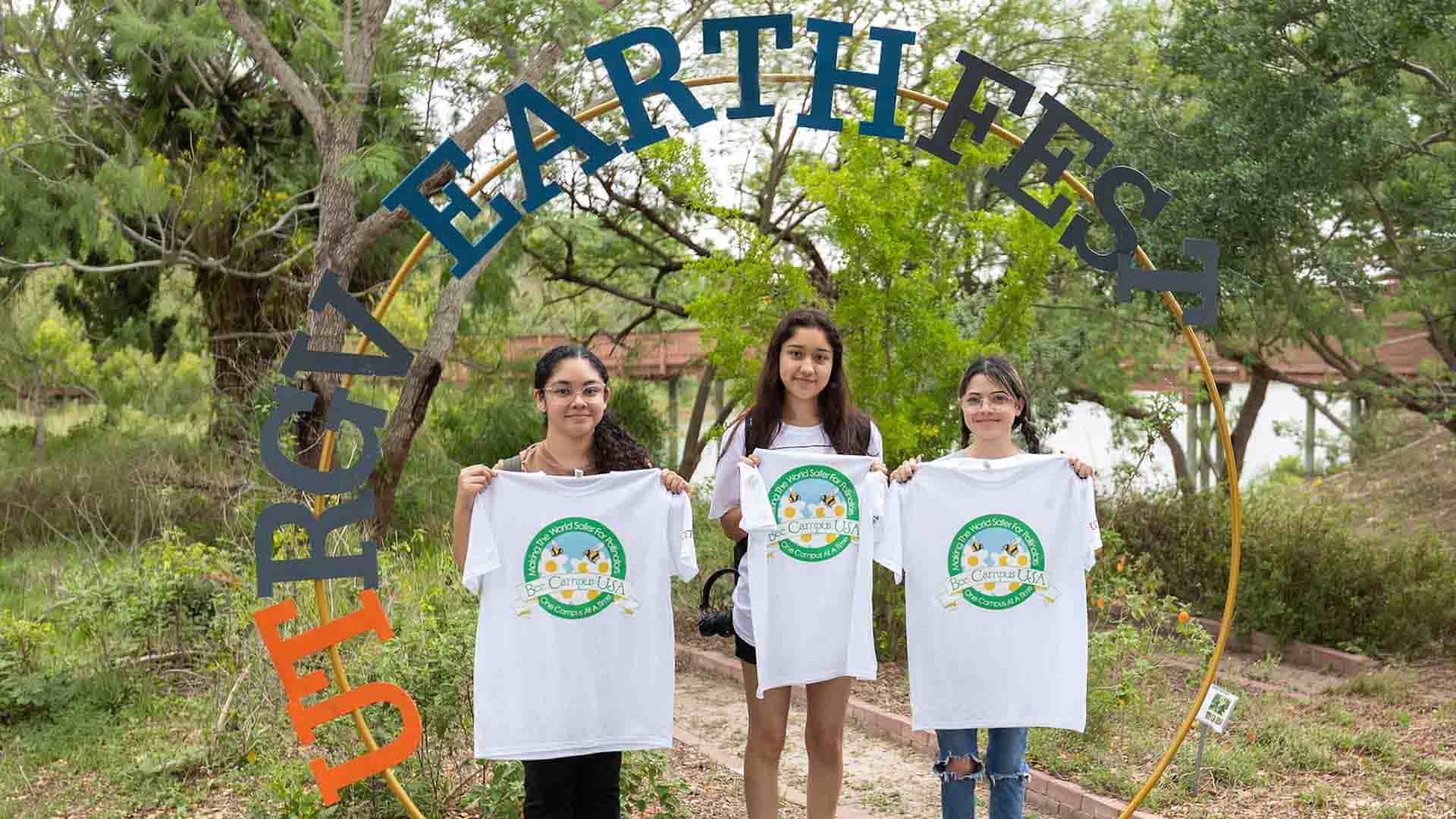 three student participants of earth Fest at utrgv holding up earth Fest promotional shirts