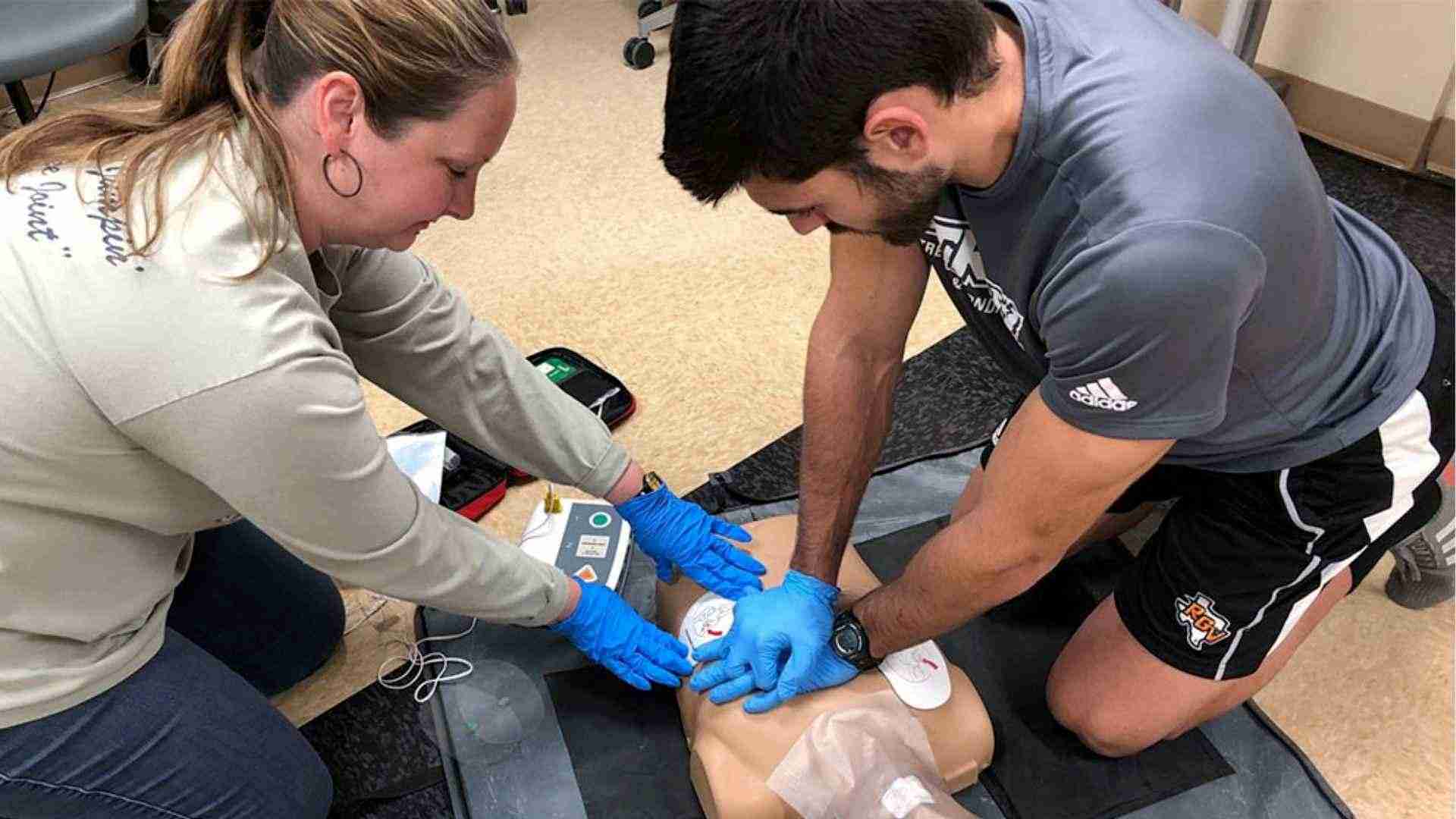 Two people practicing C.P.R on a manikin 