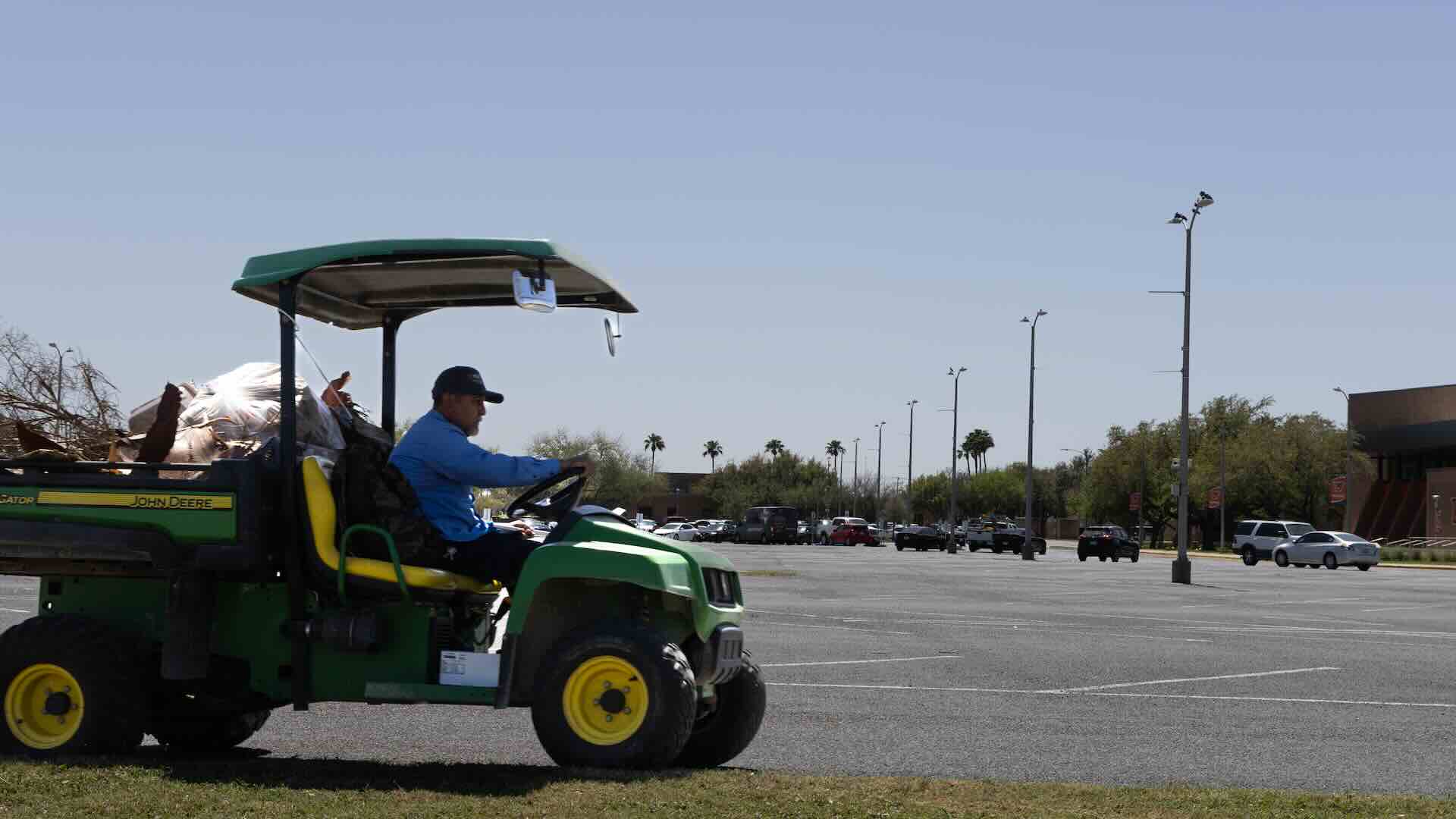 vaquero in a blue shirt worker driving across a parking lot
