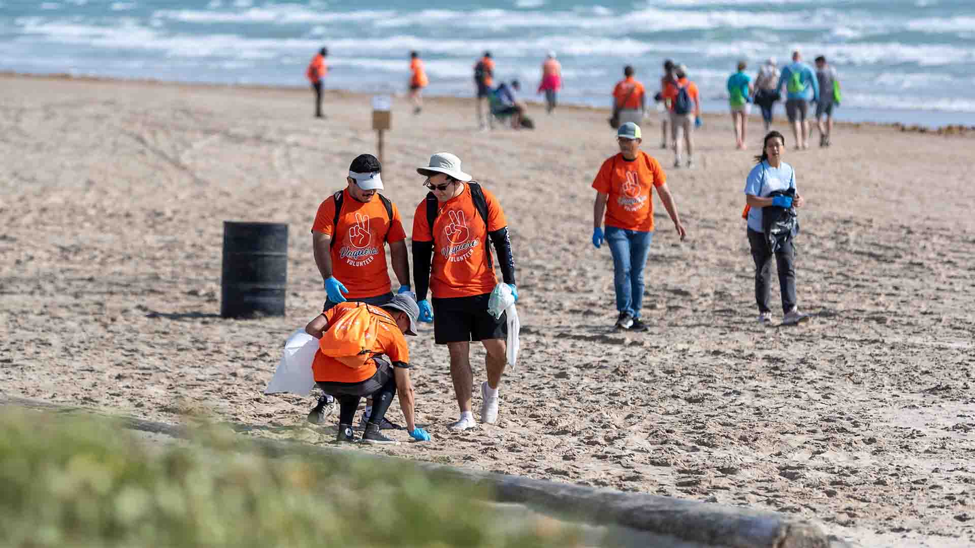 vaqueros volunteering to clean up plastics and litter on the shores of  South Padre Island